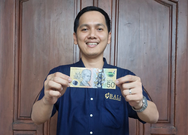 Person smiling while holding up cash earnings